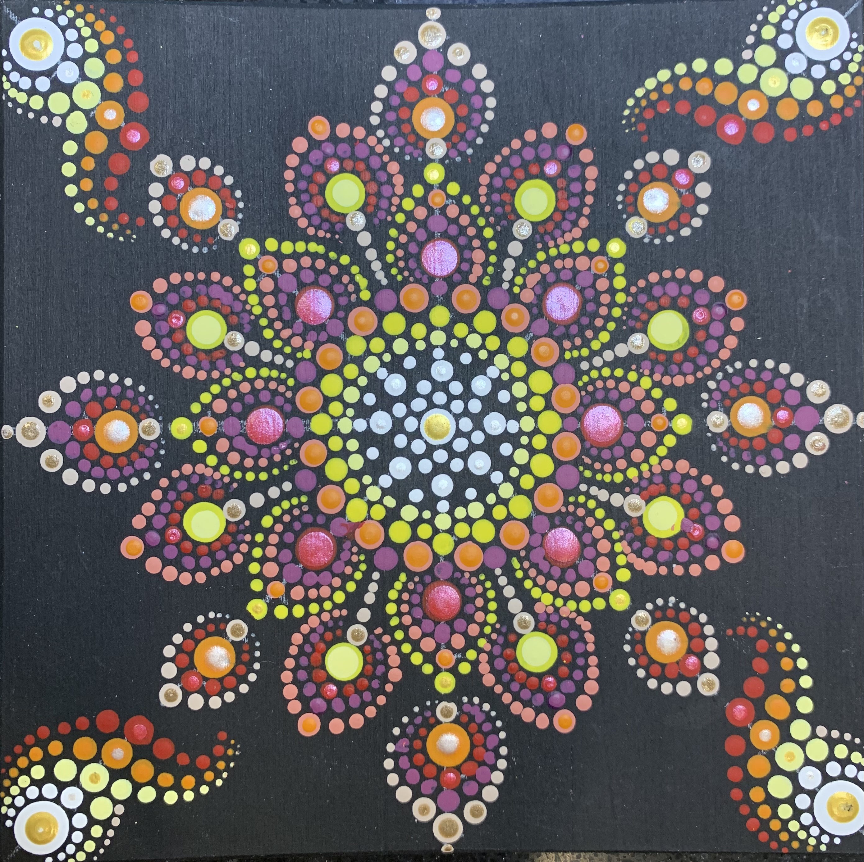 a complex pattern of tessellating, radiating out dots in white, yellow, orange, and red. The dots are on a square, black background. At each corner of the square, there is a flame pattern of dots pointing into the middle.