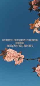 A blue sky background with pink cherry blossom in front. In the middle is text in pink font: "I am grateful for my dreams of liberation, abundance, and love for myself and others