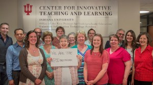 Fifteen people are standing together smiling in front of an office sign, Center for Innovative Teaching and Learning. The person in the front middle is holding the sign, "We are the #PODNetwork."
