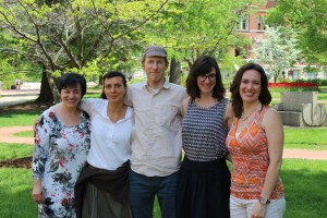 Five people are standing in a campus quad smiling.