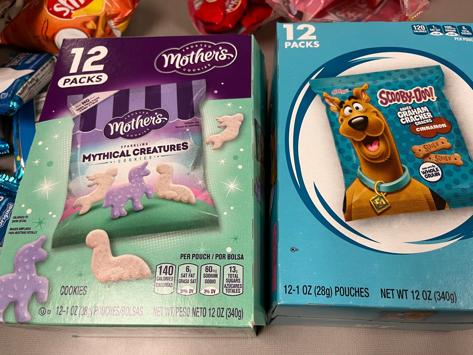 One the left is a box of Mother's Mythical Creatures cookies, on the right is a box of Scooby Doo Graham Cracker Snacks. The boxes are pastel colored.